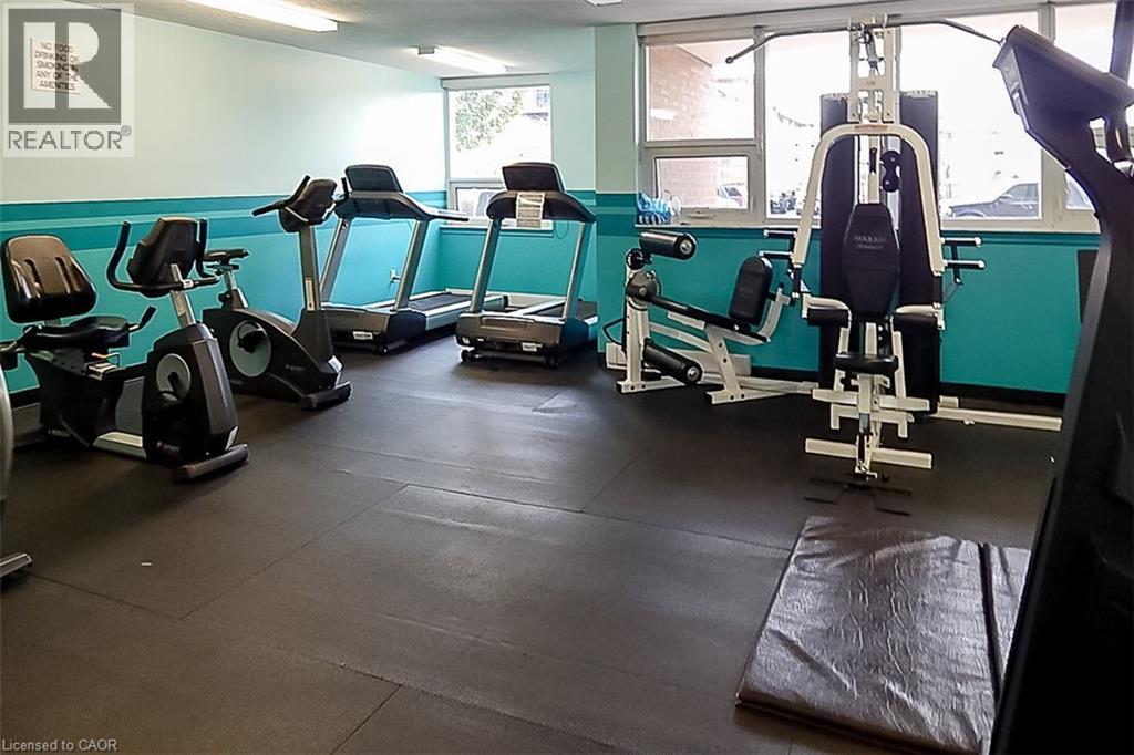 Fitness center featuring a comprehensive selection of exercise equipment, durable rubber flooring, and ample natural light from multiple windows - 500 Green Road Unit# 901, Stoney Creek, ON - Indoor Photo Showing Gym Room