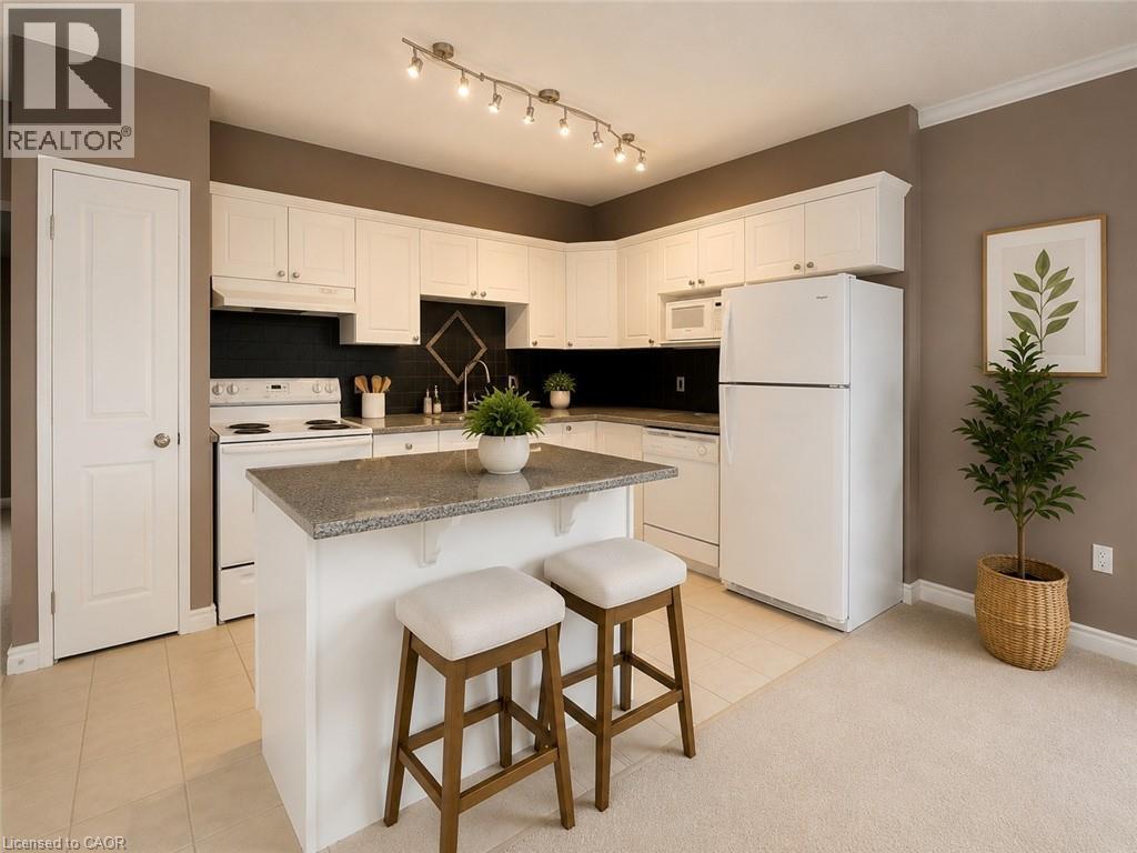 Kitchen featuring white cabinetry, a central island with a stone-finish countertop, a dark tile backsplash, and track lighting - 255 Keats Way Unit# 606, Waterloo, ON - Indoor Photo Showing Kitchen With Double Sink