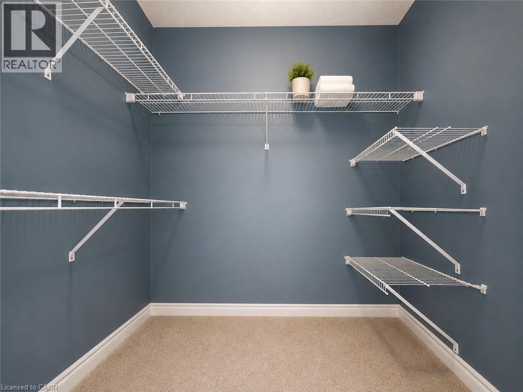 Walk-in closet with multi-level wire shelving, white baseboards, and neutral-toned carpeting - 255 Keats Way Unit# 606, Waterloo, ON - Indoor With Storage