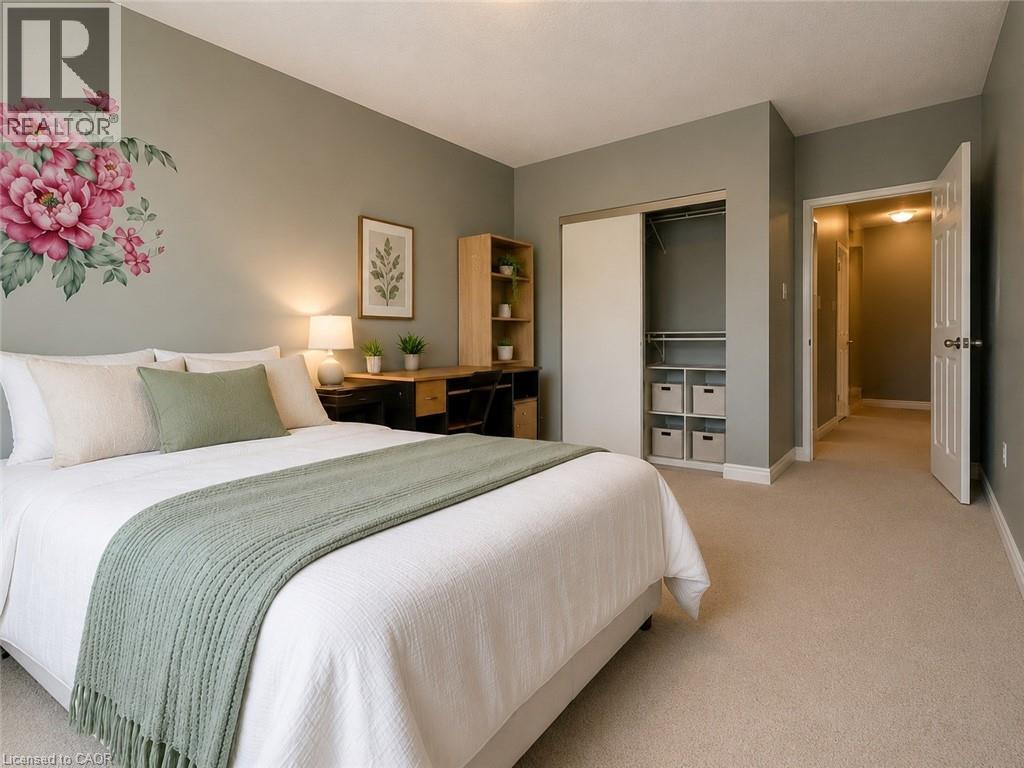 Bedroom featuring plush carpet flooring, a built-in closet with sliding doors and interior shelving, a desk area with wood-finish shelving, and a white six-panel door - 255 Keats Way Unit# 606, Waterloo, ON - Indoor Photo Showing Bedroom