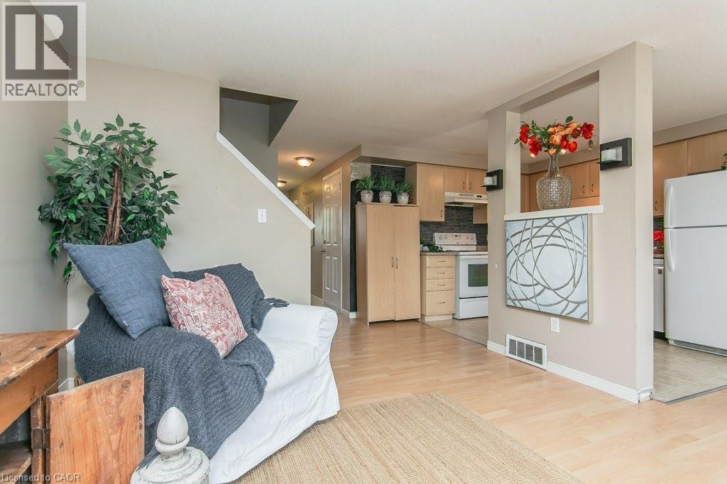 Open concept living area featuring light wood-finish flooring, a neutral paint palette, and a staircase with white risers - 71 Foxglove Crescent, Kitchener, ON - Indoor