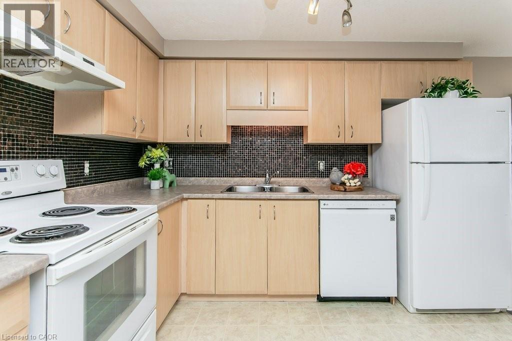 Kitchen featuring blonde wood-finish cabinetry, dark mosaic tile backsplash, and light-toned countertops - 71 Foxglove Crescent, Kitchener, ON - Indoor Photo Showing Kitchen With Double Sink