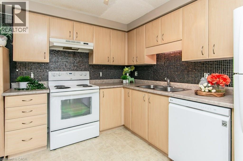 Kitchen featuring light wood-finish cabinetry, black mosaic tile backsplash, and light-toned countertops - 71 Foxglove Crescent, Kitchener, ON - Indoor Photo Showing Kitchen With Double Sink