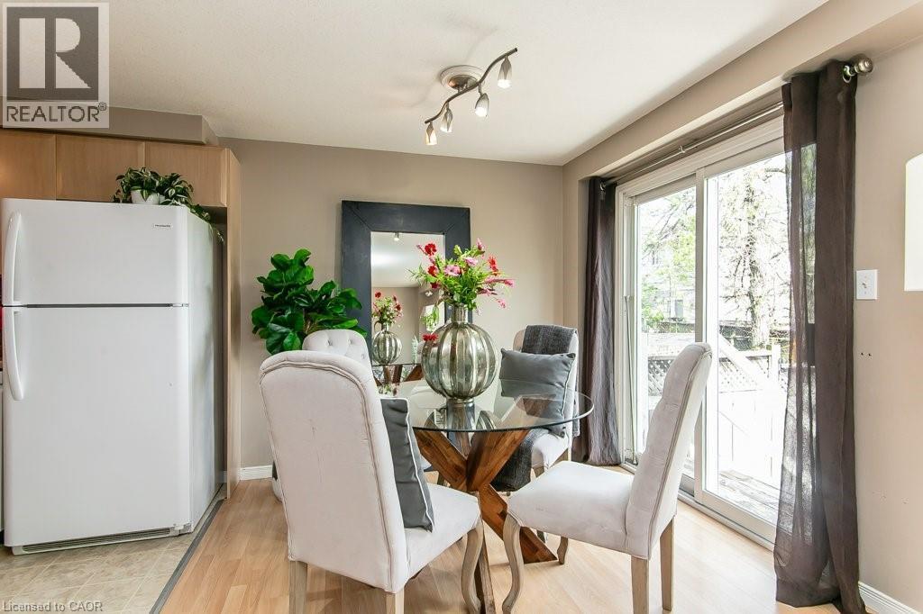 Dining area featuring wood-finish flooring, a glass-top table with a unique base, and access to an outdoor space via a sliding glass door - 71 Foxglove Crescent, Kitchener, ON - Indoor Photo Showing Dining Room