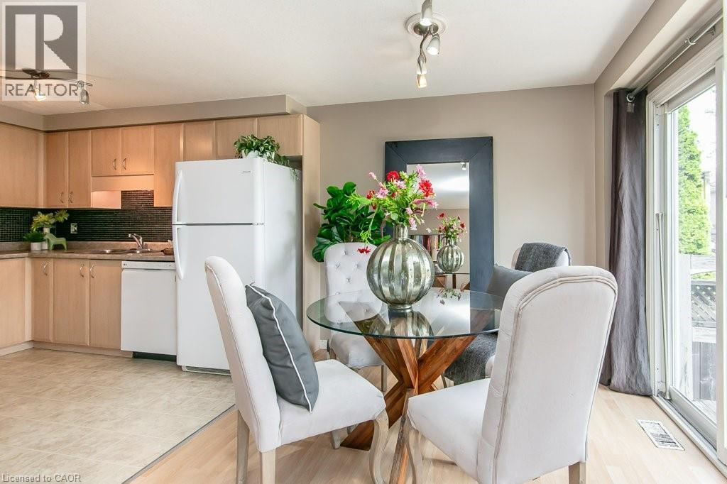 Kitchen and dining area featuring light wood cabinetry, dark tile backsplash, and a sliding glass patio door - 71 Foxglove Crescent, Kitchener, ON - Indoor Photo Showing Dining Room