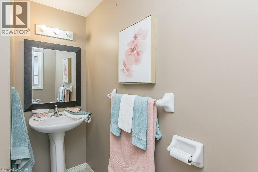 Pedestal sink with a wall-mounted faucet, framed mirror, and overhead vanity lighting - 71 Foxglove Crescent, Kitchener, ON - Indoor Photo Showing Bathroom