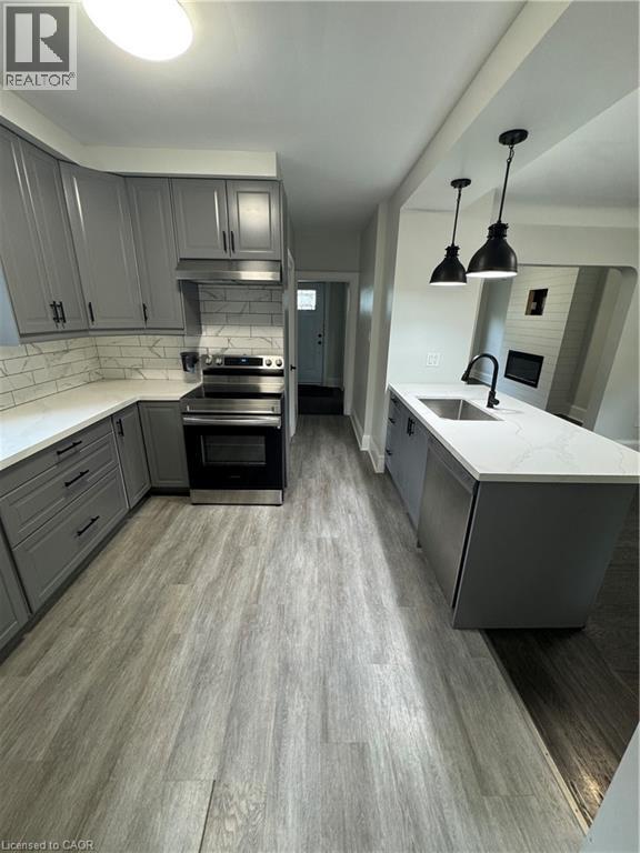 Modern kitchen featuring gray cabinetry with matte black hardware, stainless steel appliances, and white quartz countertops - 21 Haddon Avenue S, Hamilton, ON