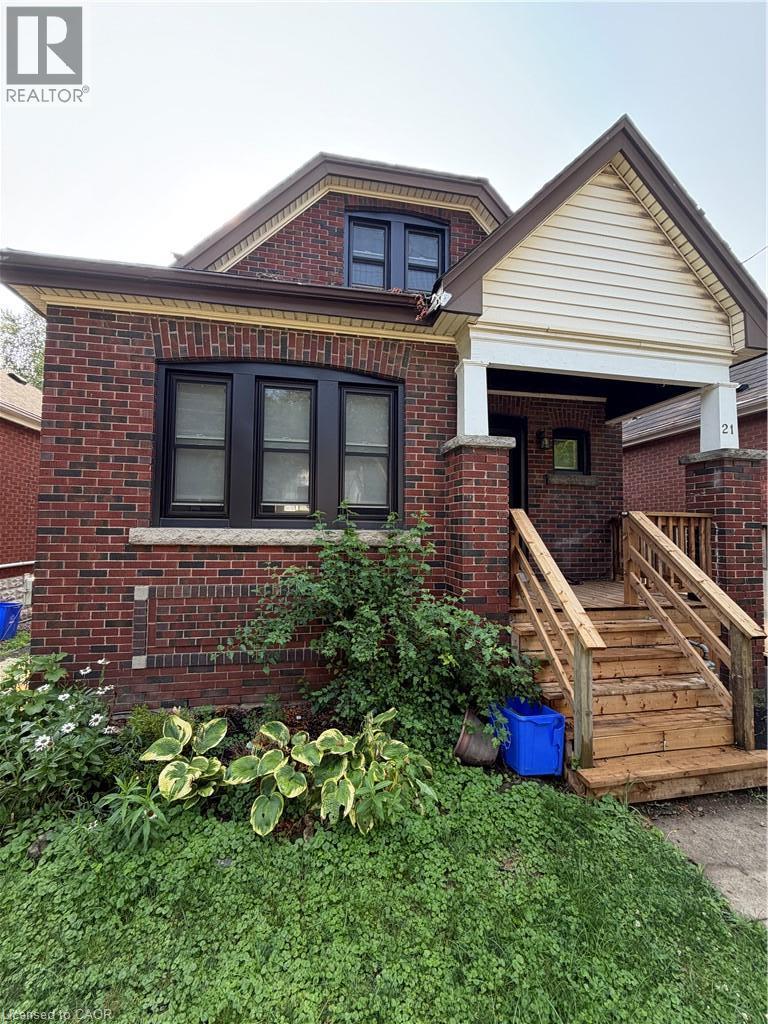 Red brick exterior with dark trim windows, front porch with white columns, and wood stairs - 21 Haddon Avenue S, Hamilton, ON - Outdoor