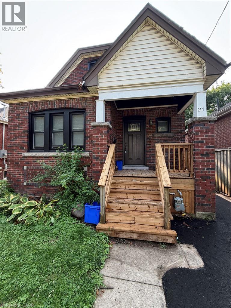 Brick exterior with a prominent front porch, wood steps, and a decorative front door - 21 Haddon Avenue S, Hamilton, ON - Outdoor