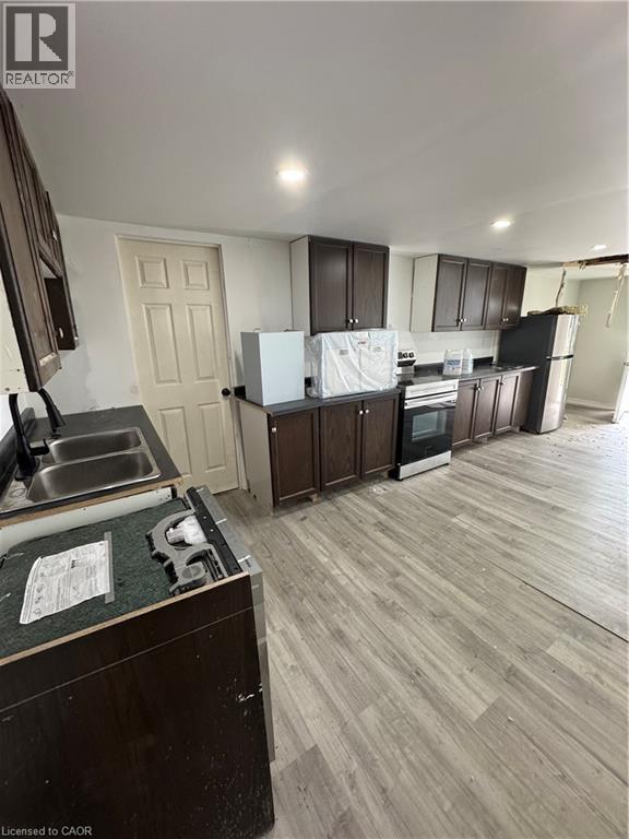 Kitchen featuring wood-finish flooring, dark wood-tone cabinetry, stainless steel sink, and recessed lighting - 28 Derner Line, Lowbanks, ON - Indoor Photo Showing Kitchen With Double Sink