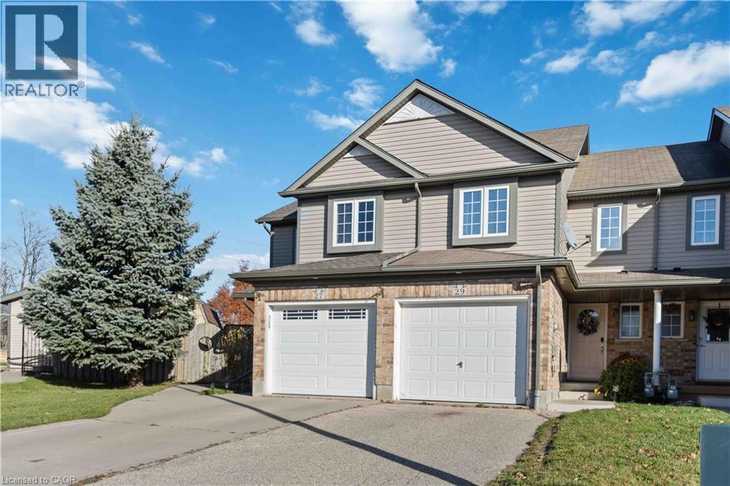 End-unit townhome featuring a two-car garage, gray siding, and brick facade accents - 27 Red Clover Crescent, Kitchener, ON - Outdoor With Facade