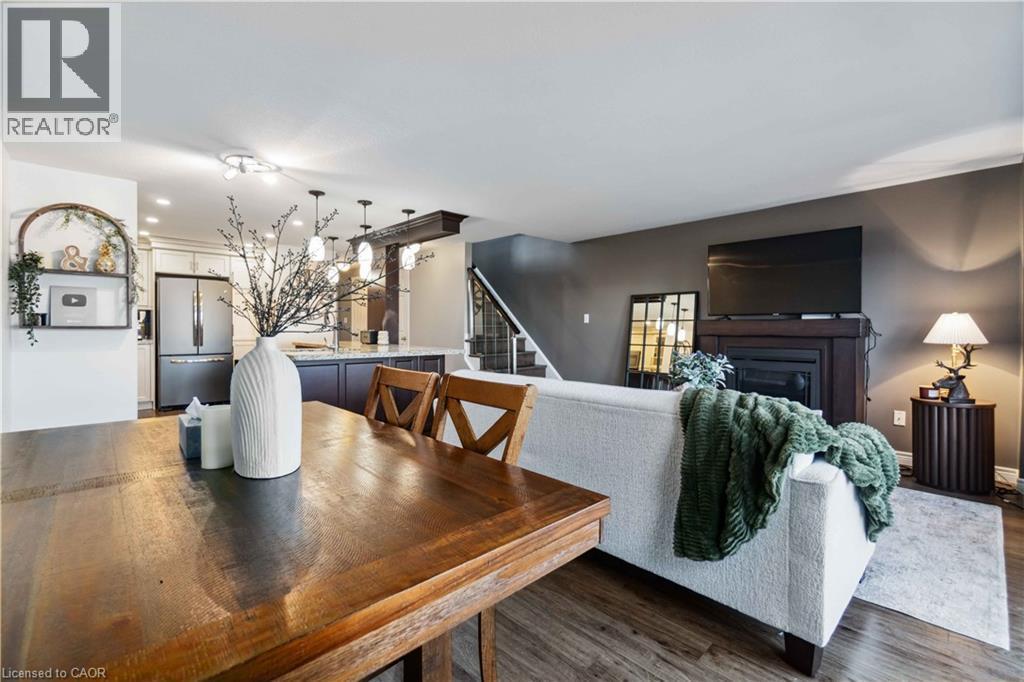 Open-concept living space featuring wood-finish flooring, a built-in fireplace with a dark wood mantel, and recessed lighting - 27 Red Clover Crescent, Kitchener, ON - Indoor Photo Showing Dining Room