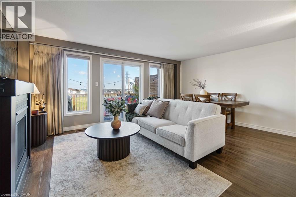 Open-concept living area featuring wood-finish flooring, a built-in electric fireplace, recessed lighting, expansive glass doors, and a large window - 27 Red Clover Crescent, Kitchener, ON - Indoor Photo Showing Living Room