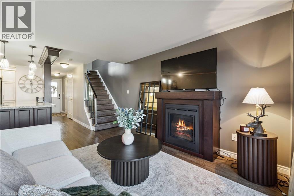 Spacious living area featuring wood-finish flooring and a staircase with dark wood treads and white risers - 27 Red Clover Crescent, Kitchener, ON - Indoor Photo Showing Living Room With Fireplace