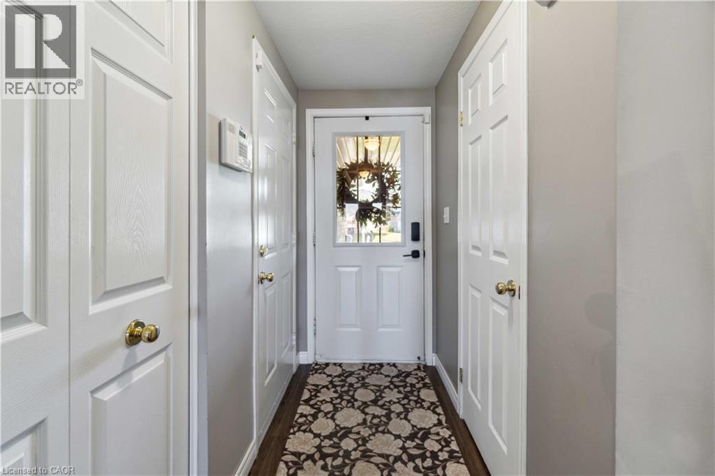 Entryway featuring a white paneled door with glass insert, wood-finish flooring, and multiple white paneled closet doors with brass hardware - 27 Red Clover Crescent, Kitchener, ON - Indoor Photo Showing Other Room