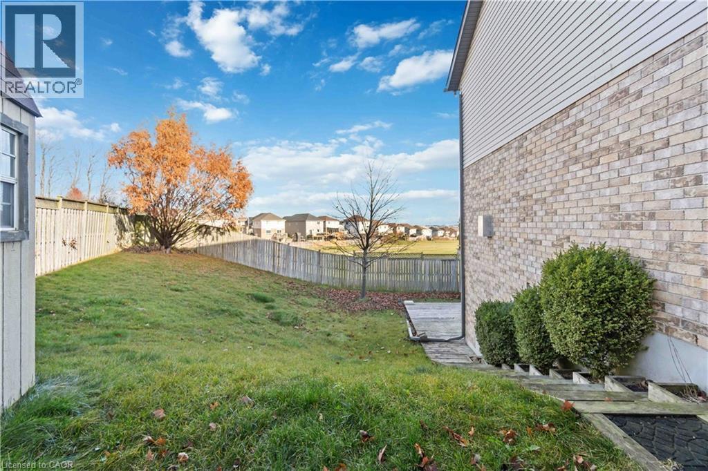 Expansive backyard featuring a manicured lawn, a privacy fence, and a mature tree - 27 Red Clover Crescent, Kitchener, ON - Outdoor