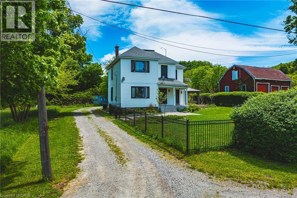 Two-story residence featuring white siding, dark window frames, and a covered front porch - 83 Webster Road, Hamilton, ON