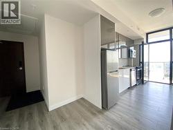 Kitchenette featuring wood-finish flooring, stainless steel appliances, white flat-panel lower cabinetry, grey high-gloss upper cabinetry, and a full-height glass patio door -