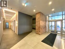 Main entrance area featuring a brick accent wall, automatic glass doors, recessed lighting, and tile flooring -