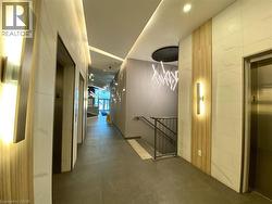 Hallway featuring multiple stainless steel elevators, large format tile flooring, and integrated ceiling lighting -