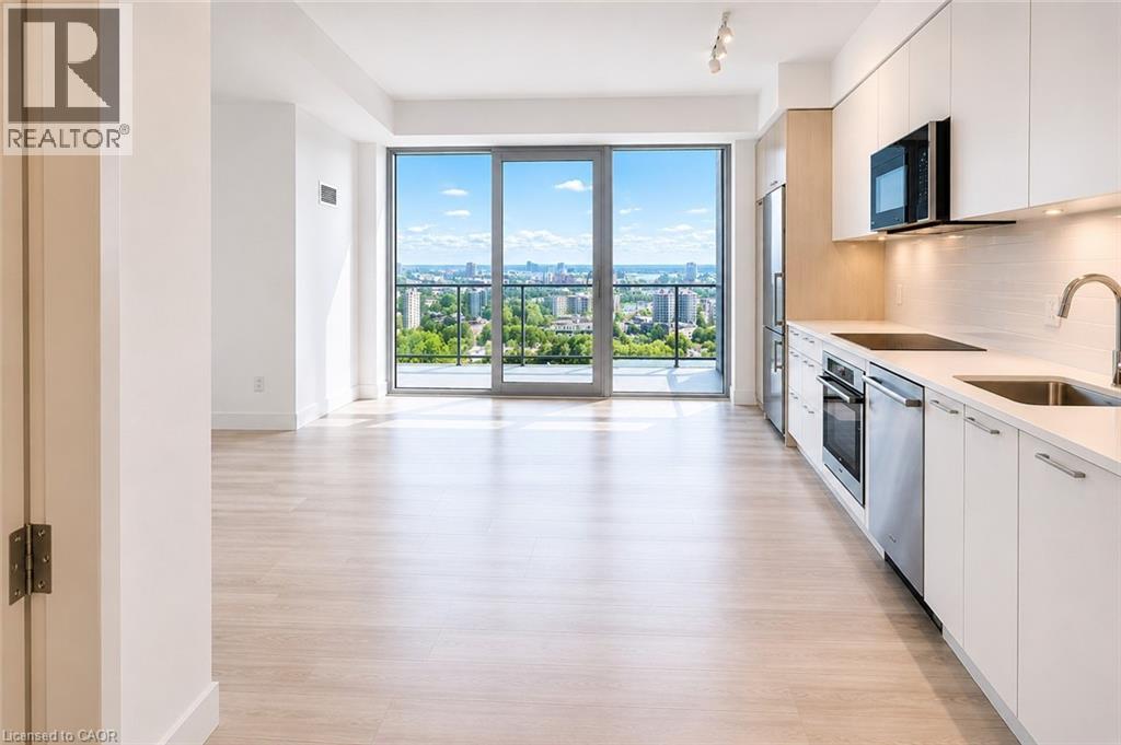 Open-concept living & dining space featuring wood-finish flooring, a contemporary kitchen with stainless steel appliances, white cabinetry, and a subway tile backsplash - 75 James Street S Unit# 2614, Hamilton, ON - Indoor Photo Showing Kitchen With Upgraded Kitchen
