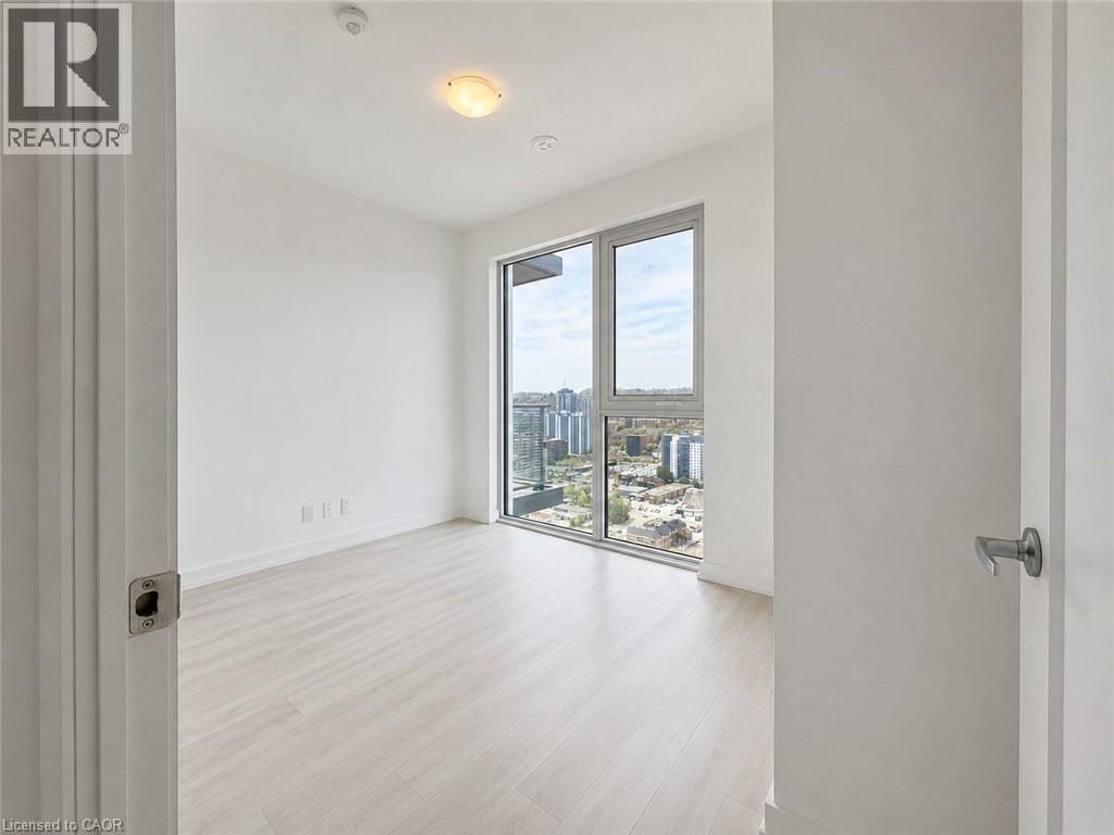 Bright room featuring a large window, light wood-finish flooring, white walls, and a ceiling-mounted light fixture - 75 James Street S Unit# 2614, Hamilton, ON - Indoor Photo Showing Other Room