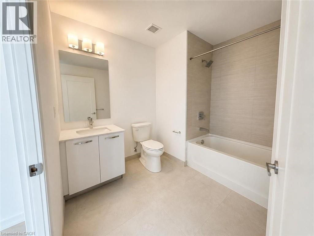 Contemporary bathroom featuring a white vanity with integrated sink, rectangular mirror, and modern three-bulb vanity lighting - 75 James Street S Unit# 2614, Hamilton, ON - Indoor Photo Showing Bathroom