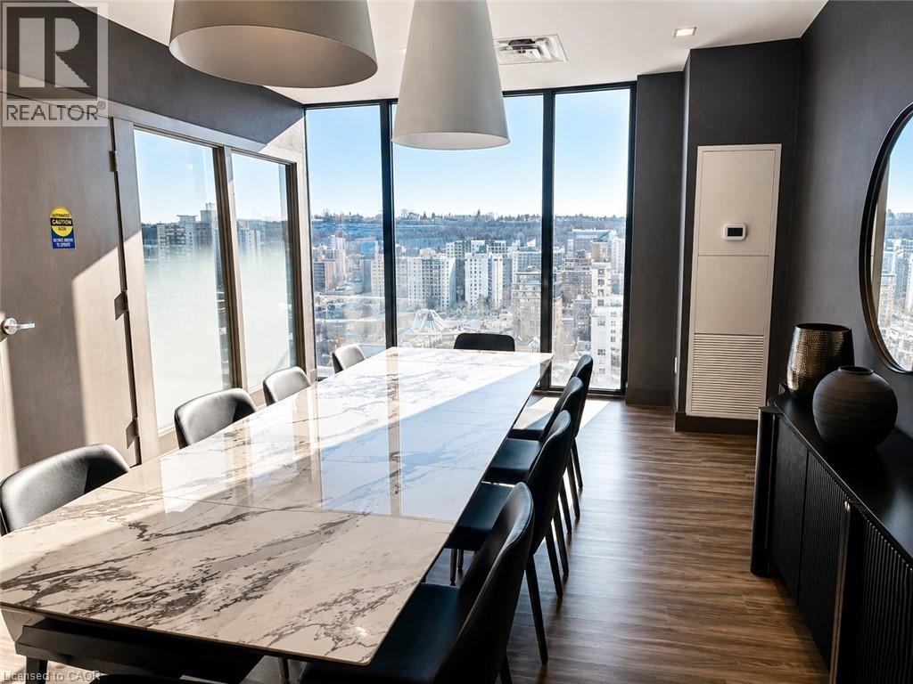 Spacious room featuring floor-to-ceiling windows, wood-finish flooring, and a large rectangular table with a patterned stone top - 75 James Street S Unit# 2614, Hamilton, ON - Indoor Photo Showing Dining Room