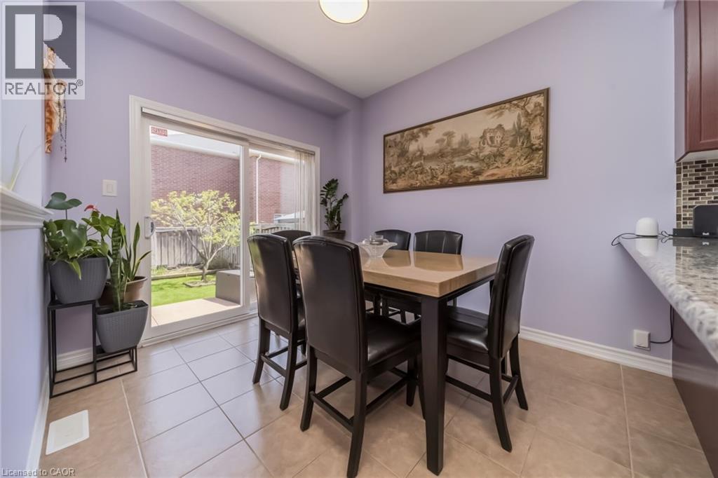 Dining area featuring neutral tile flooring, a patio door to the backyard, and a breakfast bar with a patterned backsplash - 675 Best Road, Milton, ON - Indoor Photo Showing Dining Room