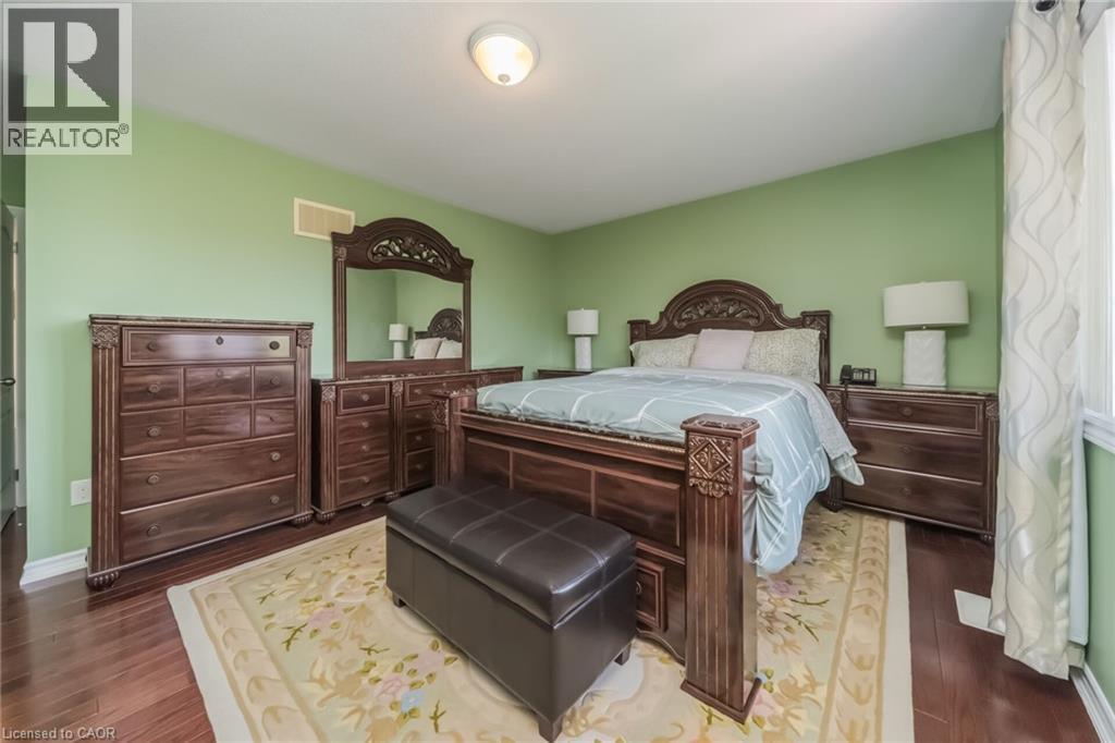 Spacious room featuring wood-finish flooring, light green walls, a single window with vertical drapery, and overhead lighting - 675 Best Road, Milton, ON - Indoor Photo Showing Bedroom