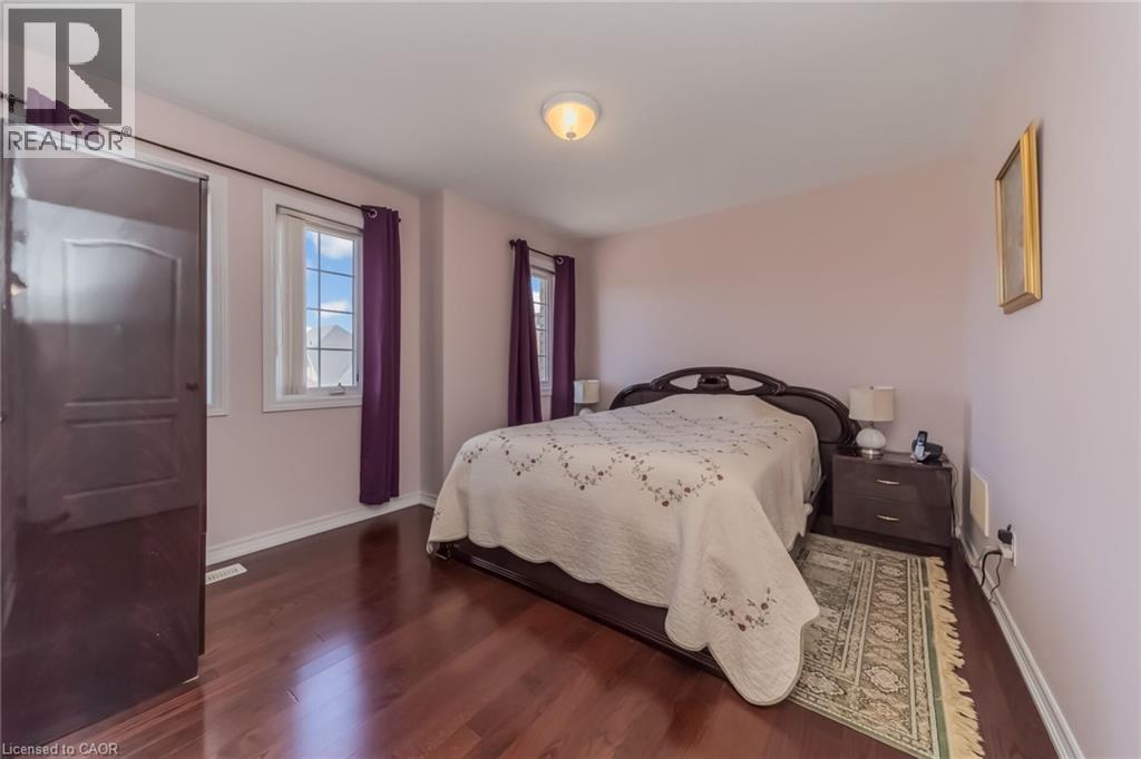 Spacious bedroom featuring rich wood-finish flooring, light-toned walls, and multiple windows - 675 Best Road, Milton, ON - Indoor Photo Showing Bedroom
