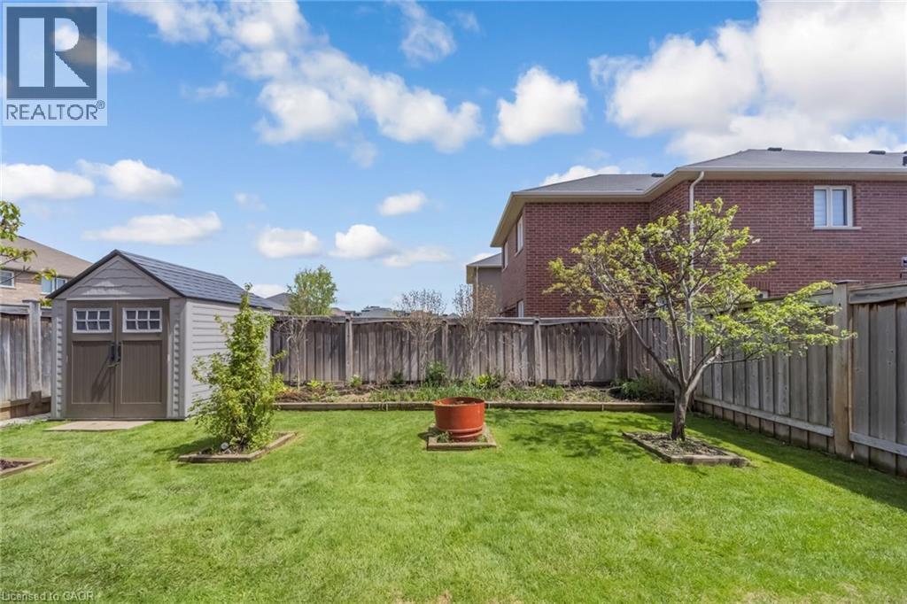 Spacious backyard featuring a manicured lawn, full privacy fencing, and a dedicated storage shed - 675 Best Road, Milton, ON - Outdoor