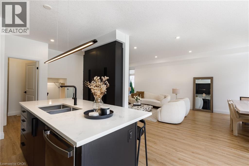 Kitchen island featuring a double-basin sink with a matte black faucet, integrated dishwasher, and a white countertop - 916 Steepleridge Court, Kitchener, ON - Indoor Photo Showing Other Room
