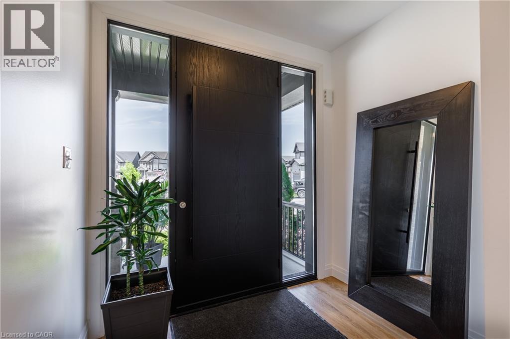 Contemporary entryway featuring a dark wood-finish door with sidelight windows, light wood-finish flooring, and crisp white walls - 916 Steepleridge Court, Kitchener, ON - Indoor Photo Showing Other Room