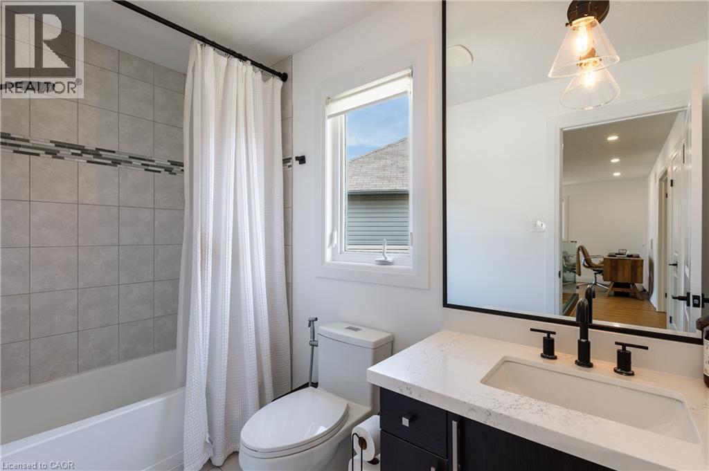 Modern bathroom featuring a single window, a dark wood-finish vanity with a white countertop, and a white rectangular undermount sink - 916 Steepleridge Court, Kitchener, ON - Indoor Photo Showing Bathroom