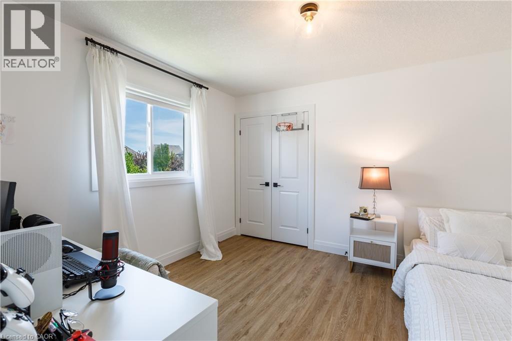 Bright room featuring wood-finish flooring, a double-panel door with black hardware, and a window with white trim and a black curtain rod - 916 Steepleridge Court, Kitchener, ON - Indoor