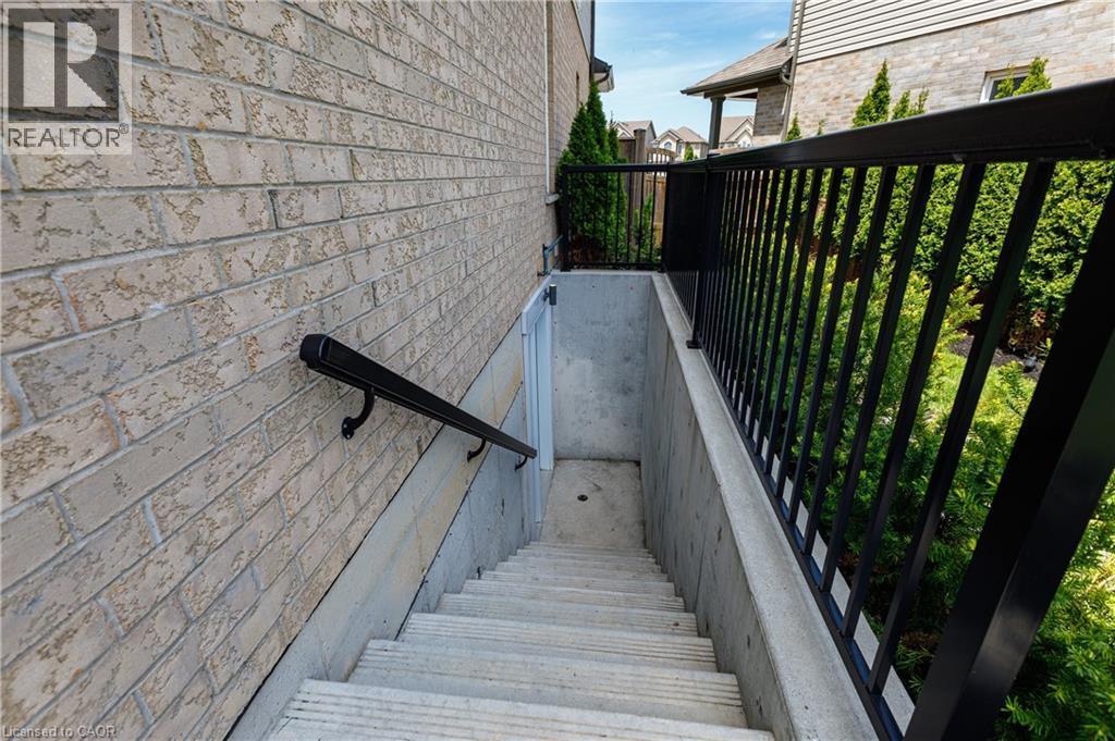 Exterior concrete stairwell featuring a black metal handrail, concrete side walls, and a light-toned brick facade - 916 Steepleridge Court, Kitchener, ON - Outdoor With Deck Patio Veranda With Exterior