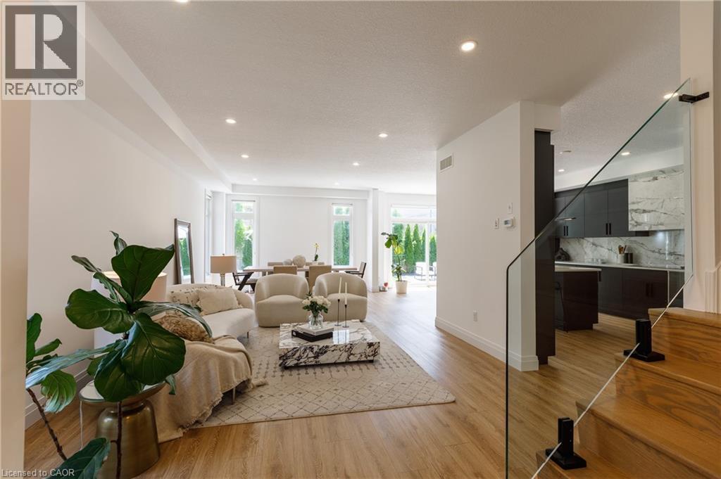 Open-concept living space featuring wood-finish flooring, recessed lighting, and a glass-paneled staircase with wood treads - 916 Steepleridge Court, Kitchener, ON - Indoor Photo Showing Other Room