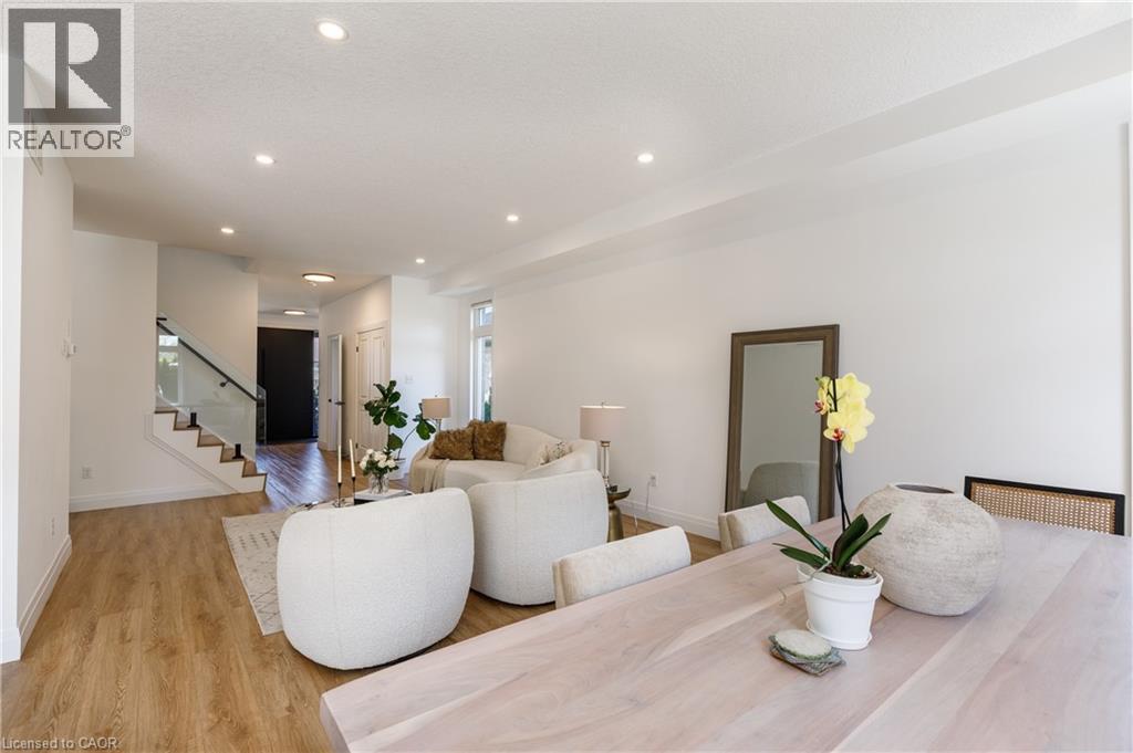Open-concept living area featuring wood-finish flooring, recessed lighting, and a modern glass staircase railing - 916 Steepleridge Court, Kitchener, ON - Indoor Photo Showing Living Room