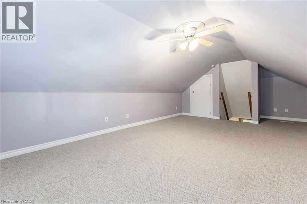 Carpeted attic space featuring a ceiling fan, sloped ceilings, and a built-in storage door - 252 Beechwood Avenue, Hamilton, ON - Indoor Photo Showing Other Room