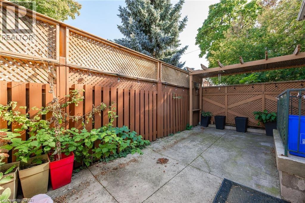 Private outdoor space featuring concrete paving and perimeter fencing with lattice details - 252 Beechwood Avenue, Hamilton, ON - Outdoor