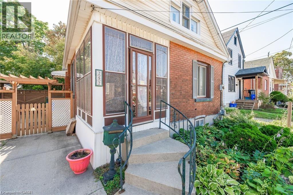 Brick and siding exterior with a screened-in porch, concrete steps, and a wrought iron handrail - 252 Beechwood Avenue, Hamilton, ON - Outdoor With Exterior