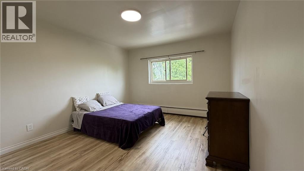 Spacious room featuring wood-finish flooring, a window offering natural light, and a ceiling-mounted light fixture - 206 Indian Road, Kitchener, ON - Indoor Photo Showing Bedroom