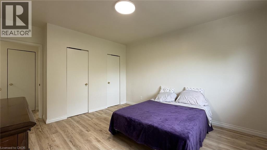 Bedroom featuring light-tone walls, wood-finish flooring, two bi-fold closet doors, and a flush-mount ceiling light - 206 Indian Road, Kitchener, ON - Indoor Photo Showing Bedroom