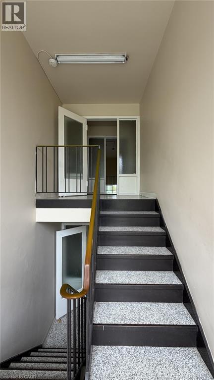 Multi-level staircase featuring speckled treads, dark risers, and a wooden handrail - 206 Indian Road, Kitchener, ON - Indoor Photo Showing Other Room