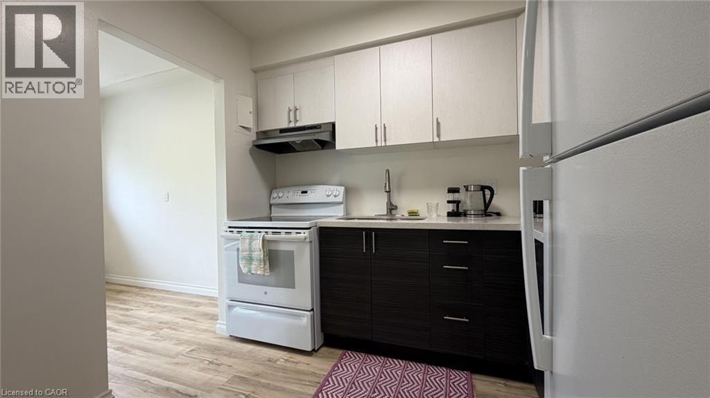 Kitchen featuring two-tone cabinetry with light upper and dark lower units, a white electric range, and a white refrigerator - 206 Indian Road, Kitchener, ON - Indoor Photo Showing Kitchen