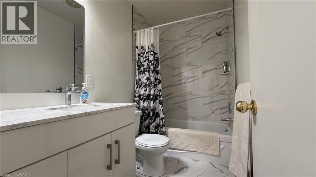 Bathroom featuring a white vanity with a light-toned countertop, a rectangular undermount sink with a chrome faucet, a wall-mounted mirror, and a white toilet - 206 Indian Road, Kitchener, ON - Indoor Photo Showing Bathroom