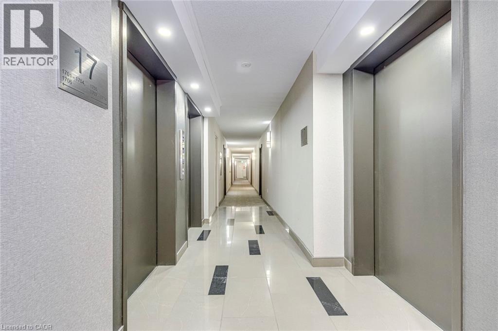 Brightly lit hallway featuring recessed lighting and wall sconces, contemporary textured wall finishes, and polished tile flooring with dark accent inlays - 1270 Maple Crossing Boulevard Unit# 1705, Burlington, ON - Indoor Photo Showing Other Room