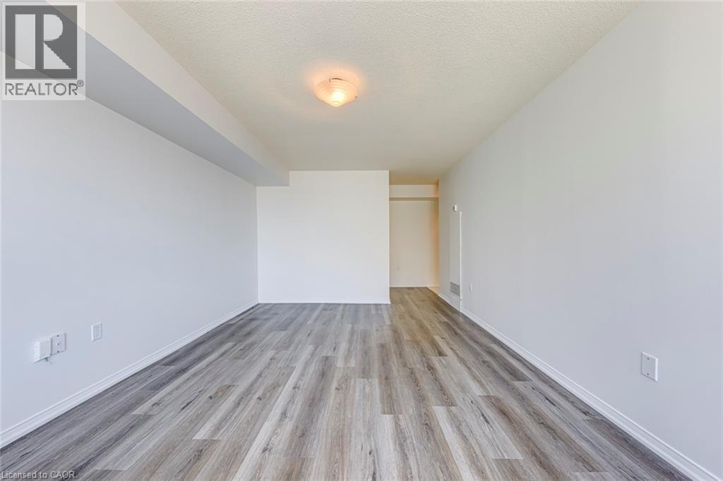 Spacious room featuring wood-finish flooring, crisp white walls, and a recessed ceiling light fixture - 1270 Maple Crossing Boulevard Unit# 1705, Burlington, ON - Indoor Photo Showing Other Room