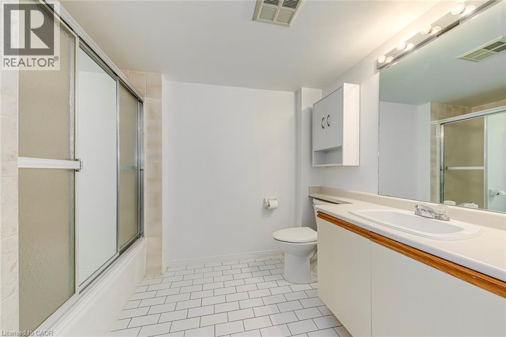 Bathroom featuring white subway tile flooring, a shower-tub combination with frosted glass sliding doors, a single vanity with a white countertop and integrated sink, a wall-mounted medicine cabinet, - 1270 Maple Crossing Boulevard Unit# 1705, Burlington, ON - Indoor Photo Showing Bathroom